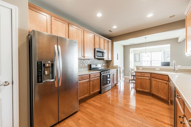 kitchen with light countertops, light wood-style floors, backsplash, and stainless steel appliances