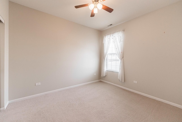 spare room with baseboards, light carpet, visible vents, and a ceiling fan