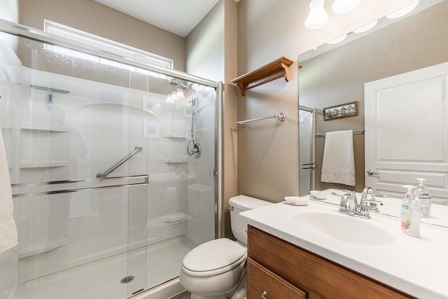 bathroom featuring a shower stall, toilet, and vanity