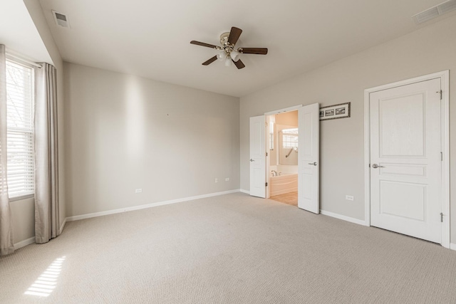 unfurnished bedroom with multiple windows, light colored carpet, visible vents, and baseboards