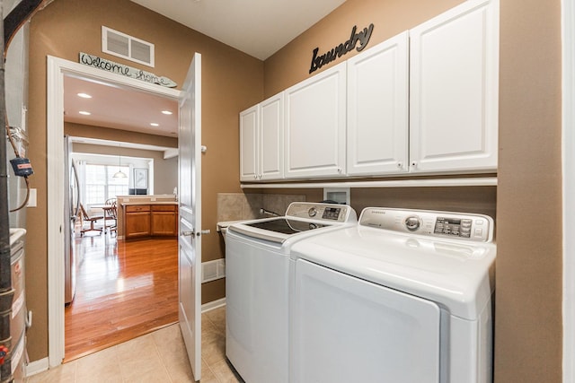 washroom with washing machine and clothes dryer, visible vents, baseboards, light tile patterned flooring, and cabinet space