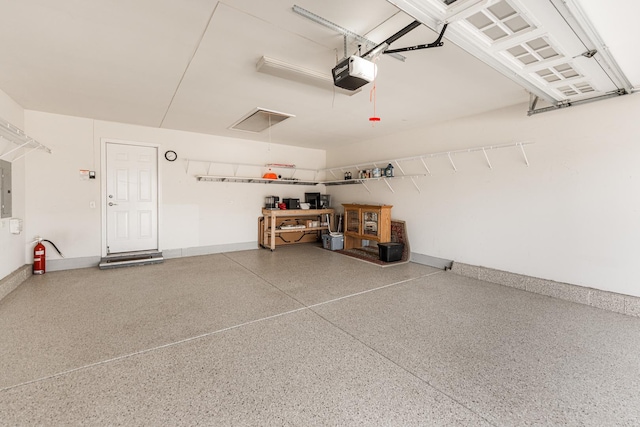 garage featuring electric panel, a garage door opener, and baseboards