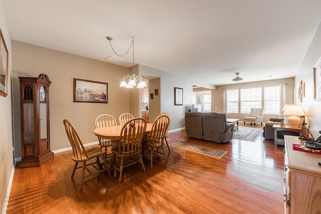 dining room with visible vents, baseboards, light wood-type flooring, and an inviting chandelier