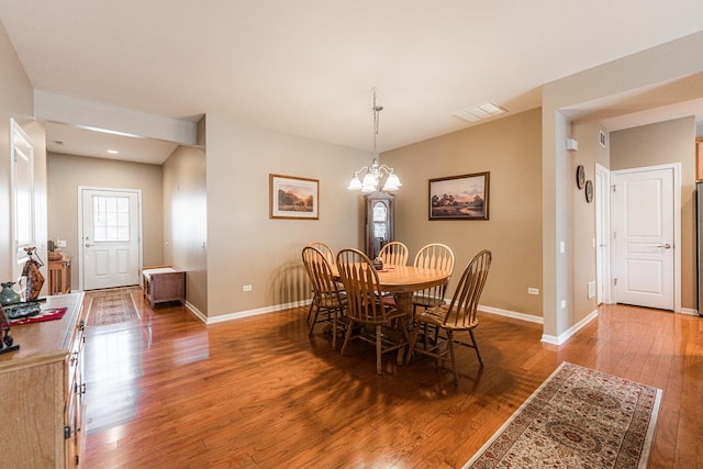 dining area with a chandelier, visible vents, baseboards, and hardwood / wood-style flooring