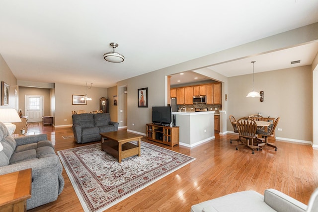 living room featuring visible vents, light wood-style flooring, and baseboards