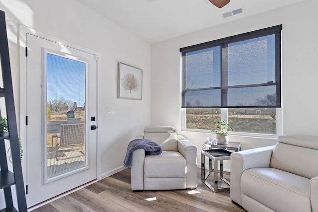 living area featuring wood finished floors, visible vents, and baseboards