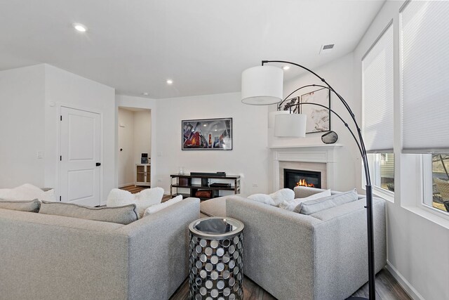 living area featuring wood finished floors, visible vents, baseboards, recessed lighting, and a glass covered fireplace