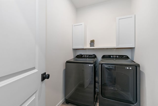 laundry area with baseboards, cabinet space, and washer and clothes dryer