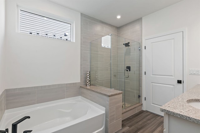 full bath with a stall shower, vanity, a garden tub, and wood finished floors