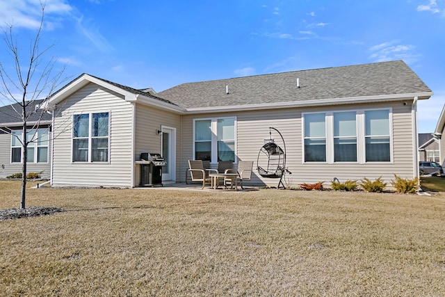 rear view of property featuring a patio area, a shingled roof, and a yard