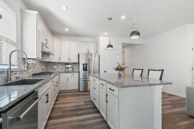 kitchen featuring backsplash, a center island, dark wood-style floors, stainless steel appliances, and a sink