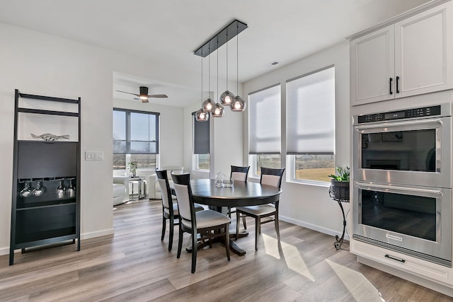 dining room featuring light wood finished floors, ceiling fan, and baseboards