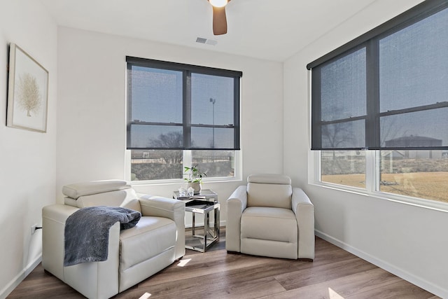 sitting room with a ceiling fan, wood finished floors, visible vents, and baseboards