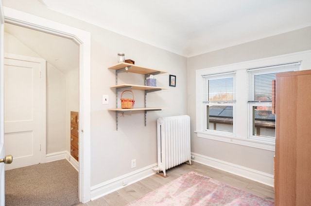 unfurnished room featuring light wood-style floors, baseboards, and radiator