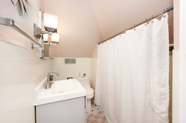 full bathroom featuring visible vents, tile walls, toilet, vaulted ceiling, and vanity