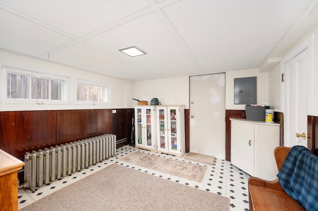 interior space featuring electric panel, a wainscoted wall, radiator, and wood walls