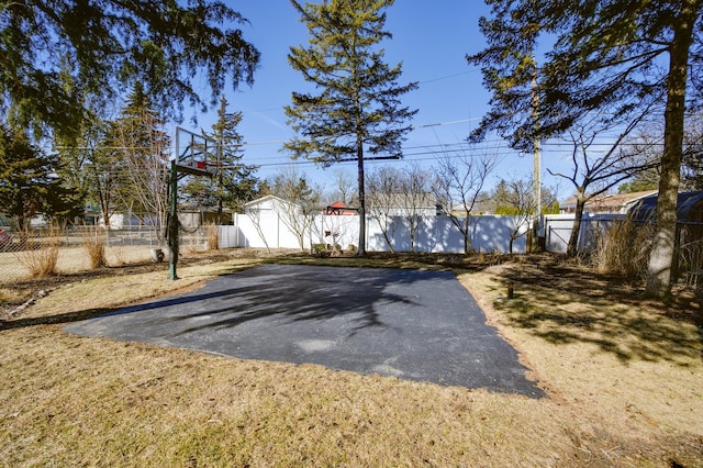 view of yard featuring an outbuilding, a storage shed, a fenced backyard, and basketball court