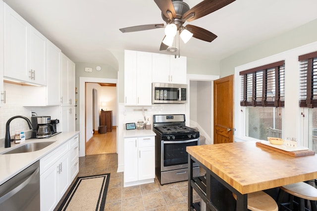 kitchen featuring white cabinets, stainless steel appliances, light countertops, and a sink