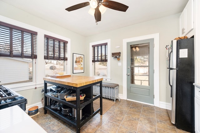 kitchen with white cabinets, radiator heating unit, baseboards, and freestanding refrigerator