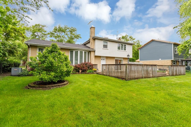 back of house featuring brick siding, a chimney, a deck, and a lawn