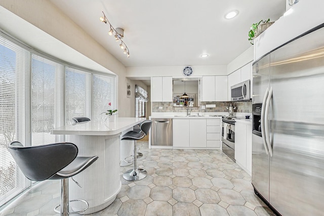 kitchen with a sink, appliances with stainless steel finishes, a kitchen breakfast bar, and a wealth of natural light