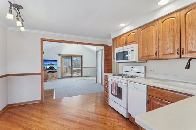 kitchen with crown molding, light countertops, light wood-style floors, white appliances, and a sink