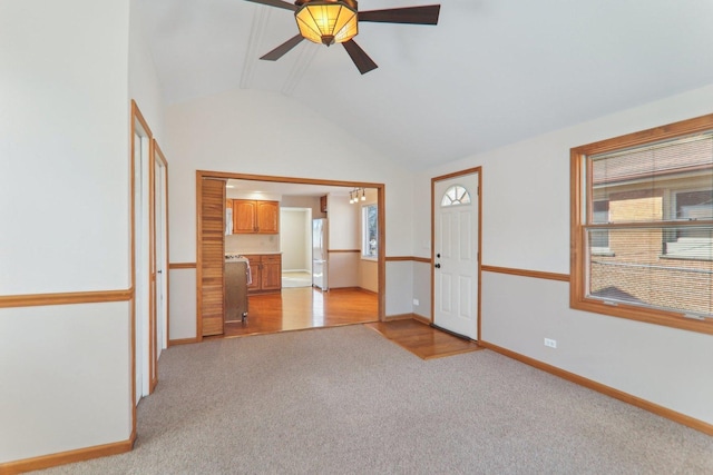 empty room featuring light carpet, a healthy amount of sunlight, baseboards, and vaulted ceiling