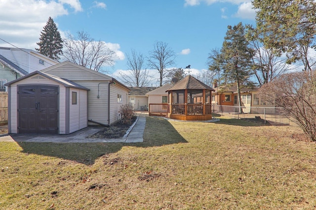 rear view of house with a gazebo, a lawn, fence, and an outbuilding