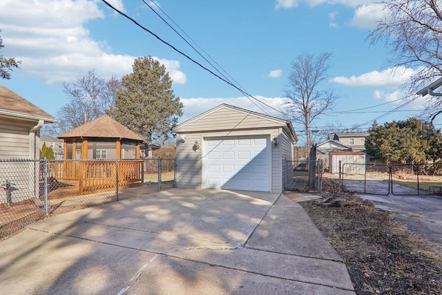 detached garage with concrete driveway, fence, and a gate