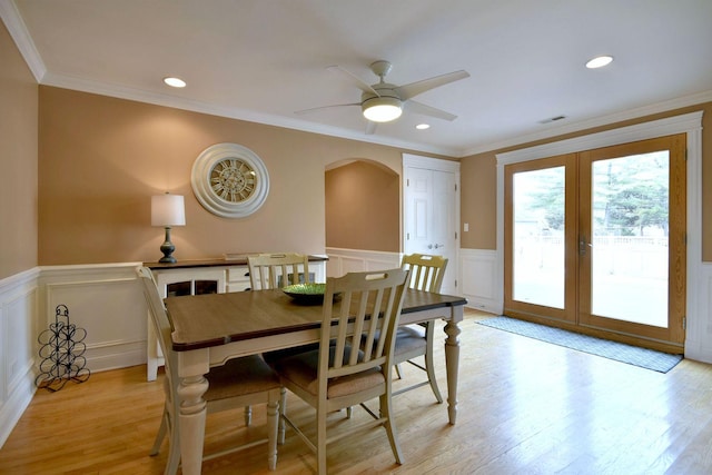 dining room featuring arched walkways, visible vents, wainscoting, and light wood-type flooring