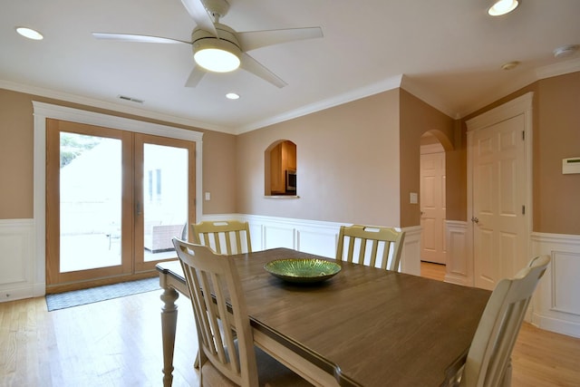 dining space featuring visible vents, light wood-style flooring, a wainscoted wall, and ornamental molding