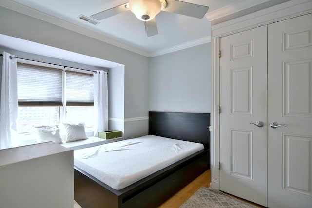 bedroom featuring crown molding, a ceiling fan, visible vents, and light wood finished floors