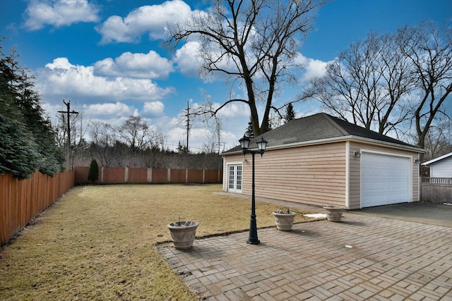 view of yard featuring an outbuilding, driveway, a fenced backyard, french doors, and a garage