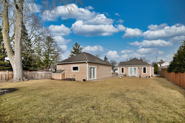 rear view of property featuring a fenced backyard, an outbuilding, and a yard