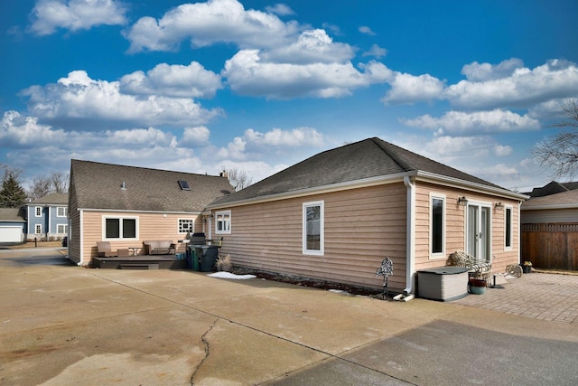 back of property with a patio, roof with shingles, and fence