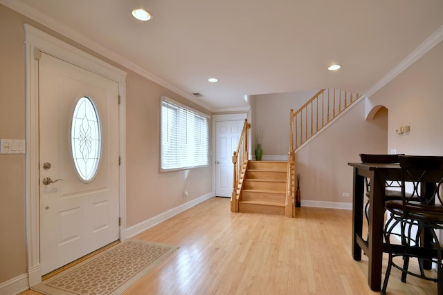 entryway featuring light wood finished floors, baseboards, stairway, ornamental molding, and arched walkways