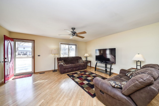 living area featuring light wood-style flooring, a ceiling fan, and baseboards