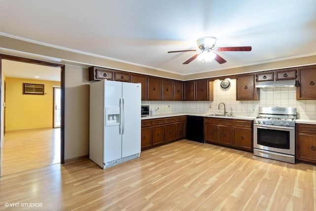 kitchen featuring white refrigerator with ice dispenser, light wood finished floors, stainless steel gas stove, a sink, and dishwasher