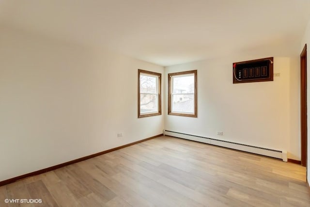 unfurnished room with a baseboard heating unit, light wood-type flooring, and baseboards