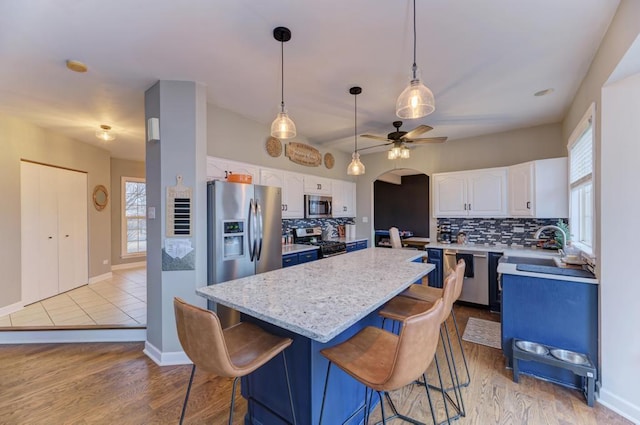 kitchen with stainless steel appliances, decorative backsplash, white cabinets, and a center island