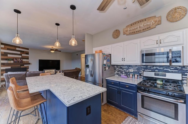 kitchen featuring a center island, stainless steel appliances, backsplash, ceiling fan, and blue cabinets