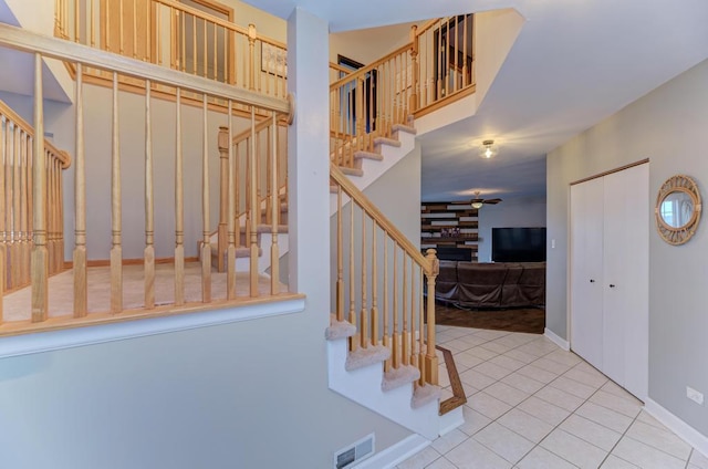 stairs featuring tile patterned flooring, a fireplace, visible vents, baseboards, and a ceiling fan