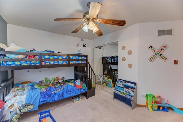 carpeted bedroom with a closet, visible vents, and ceiling fan