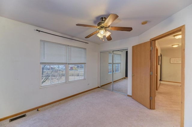 unfurnished bedroom with light colored carpet, a ceiling fan, baseboards, visible vents, and a closet