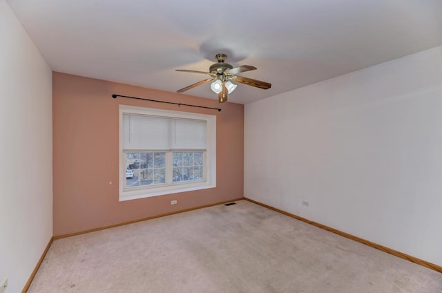 empty room with light carpet, a ceiling fan, visible vents, and baseboards