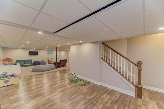 rec room with a paneled ceiling, baseboards, wood finished floors, and recessed lighting