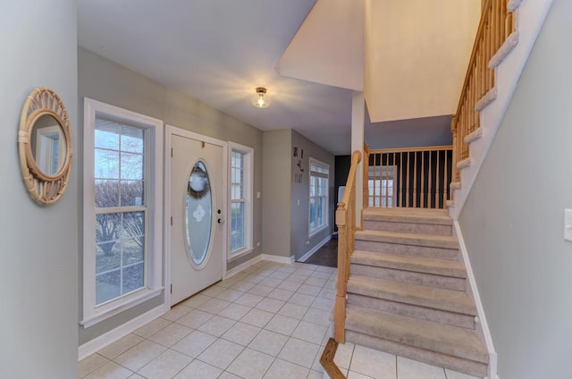 entryway with stairway, light tile patterned flooring, and baseboards