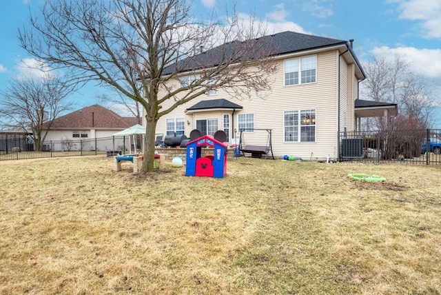 rear view of house featuring a lawn and fence