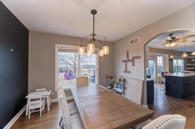 dining room featuring baseboards, visible vents, arched walkways, a ceiling fan, and dark wood-style floors