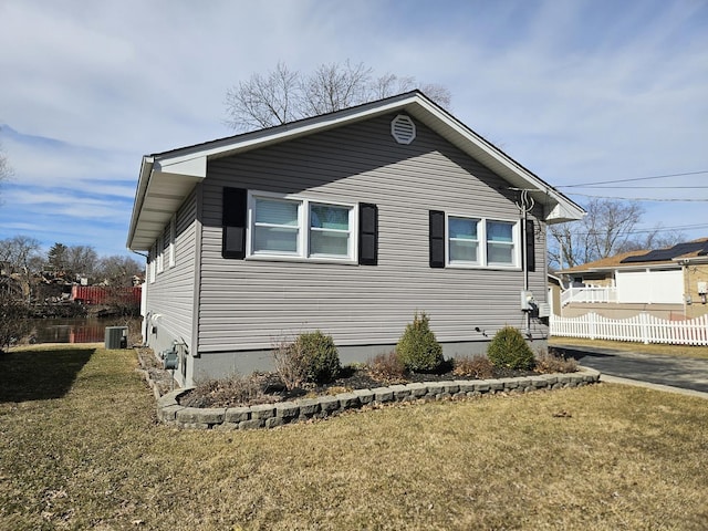 view of side of home featuring a yard, central air condition unit, and fence